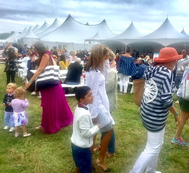 Family crowd at outdoor festival under white tents