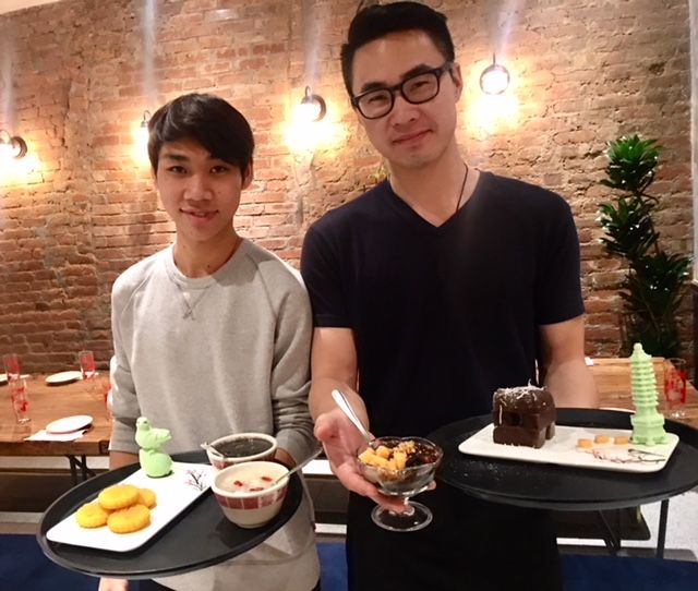 Two people holding dessert trays in restaurant