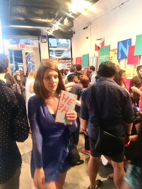 Woman in blue dress holding sign at gallery