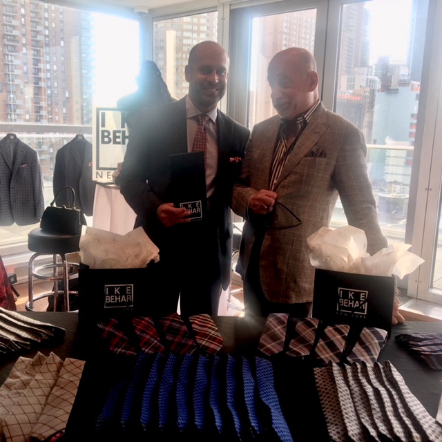 Two men examining ties at showroom table