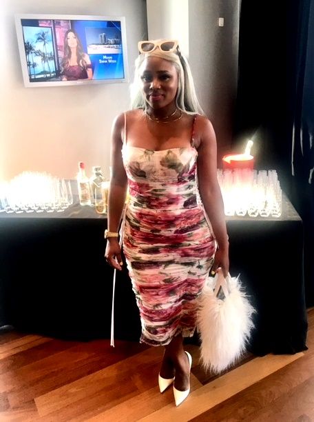 Woman in floral midi dress holding white handbag