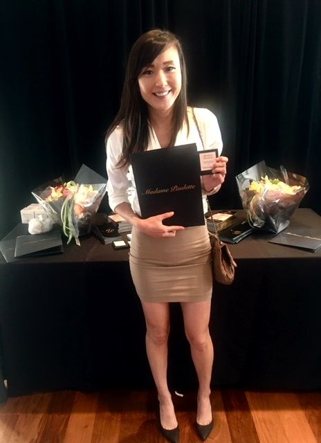 Smiling woman holding certificate, bouquets on table