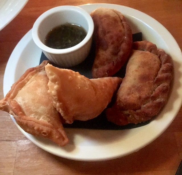 Plate of empanadas with green dipping sauce