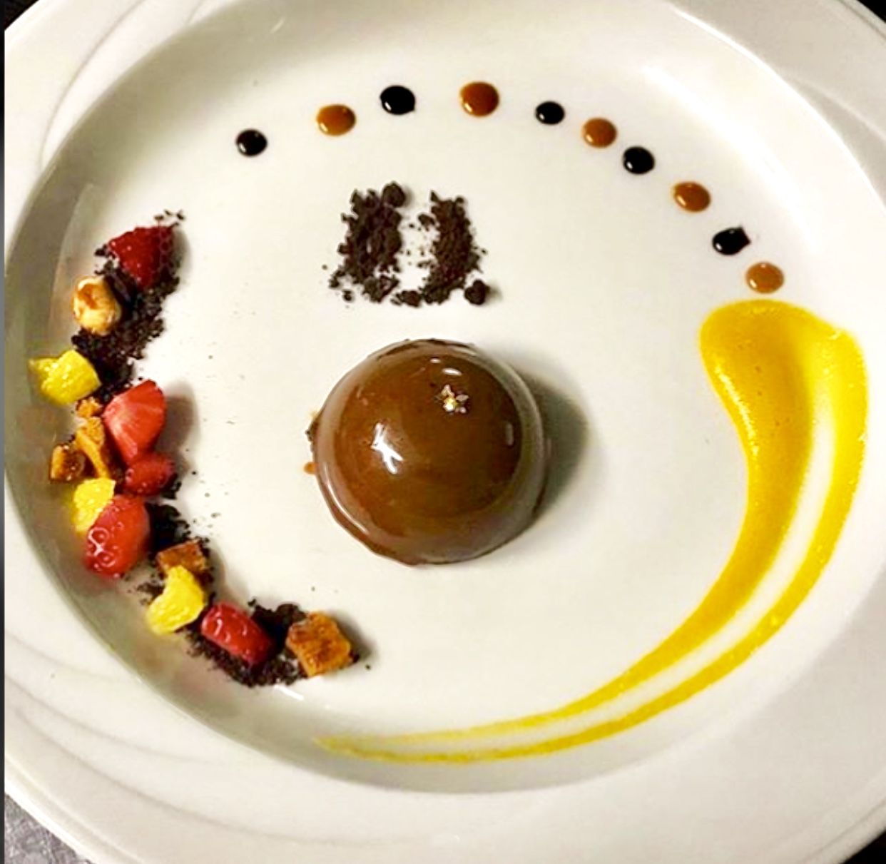 Glazed chocolate dome with fruit and sauces
