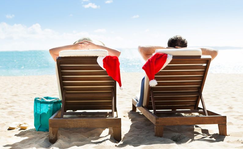 Couple relaxing on beach chairs with Santa hats