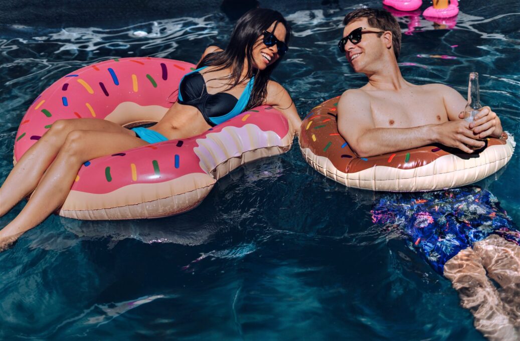 Couple lounging on donut floats in pool