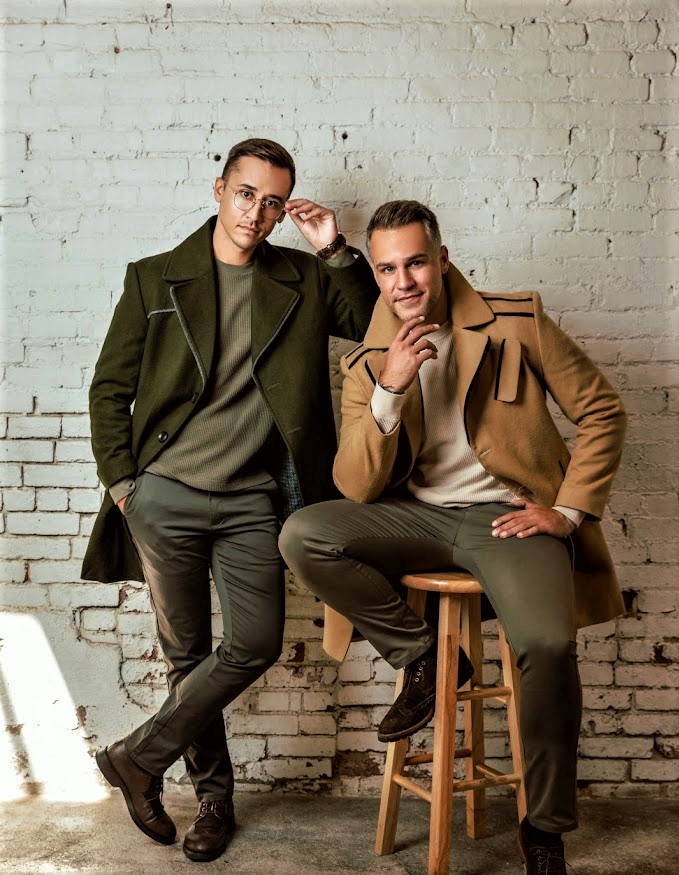 Two stylish men in coats by brick wall