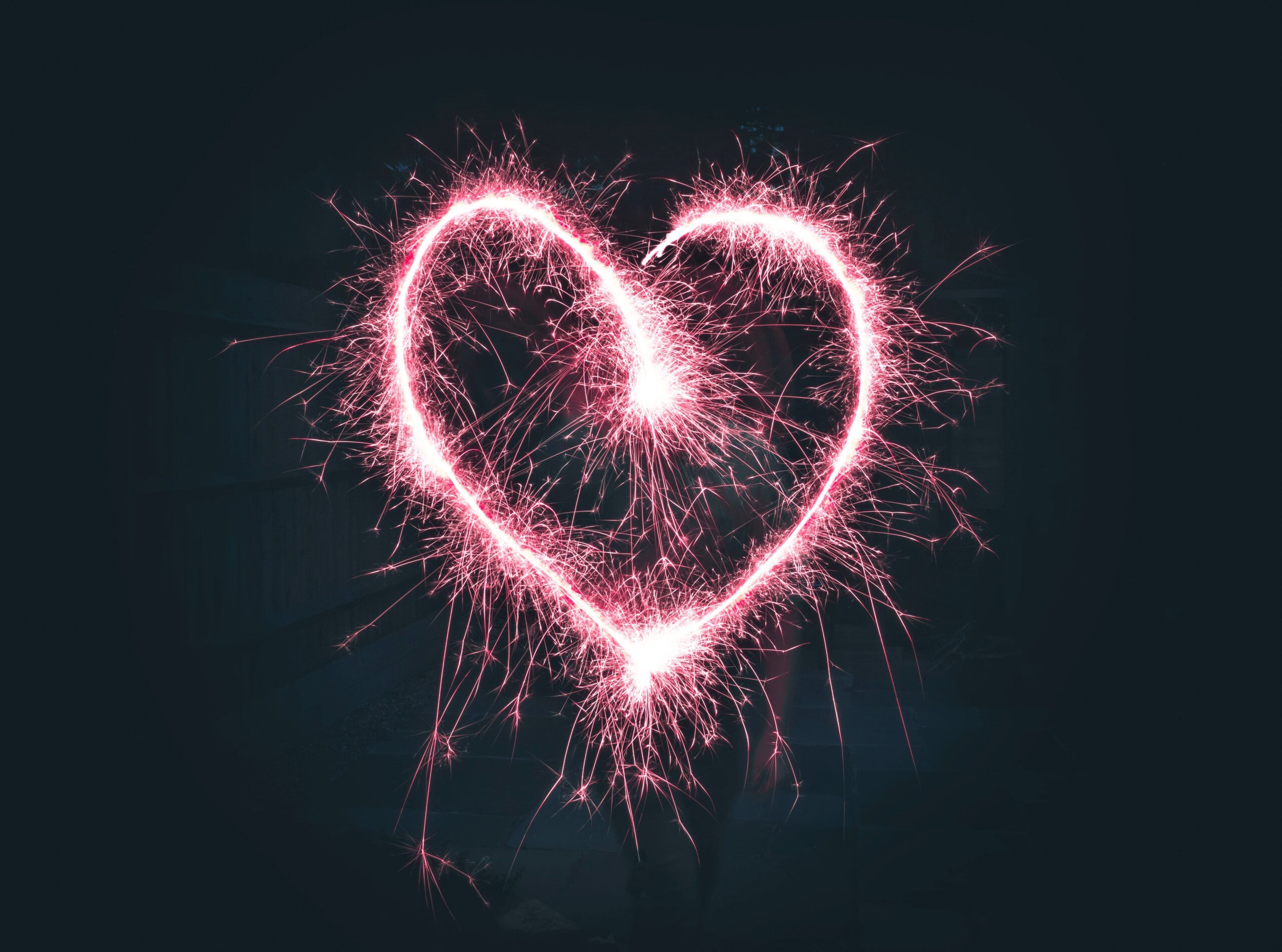 Glowing pink sparkler heart on dark background