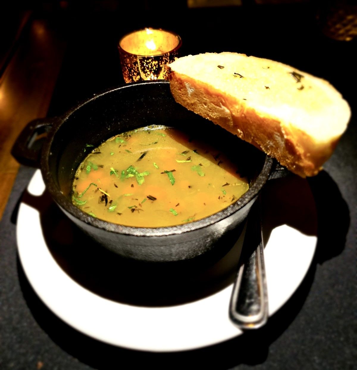 Herb-garnished soup in pot with bread