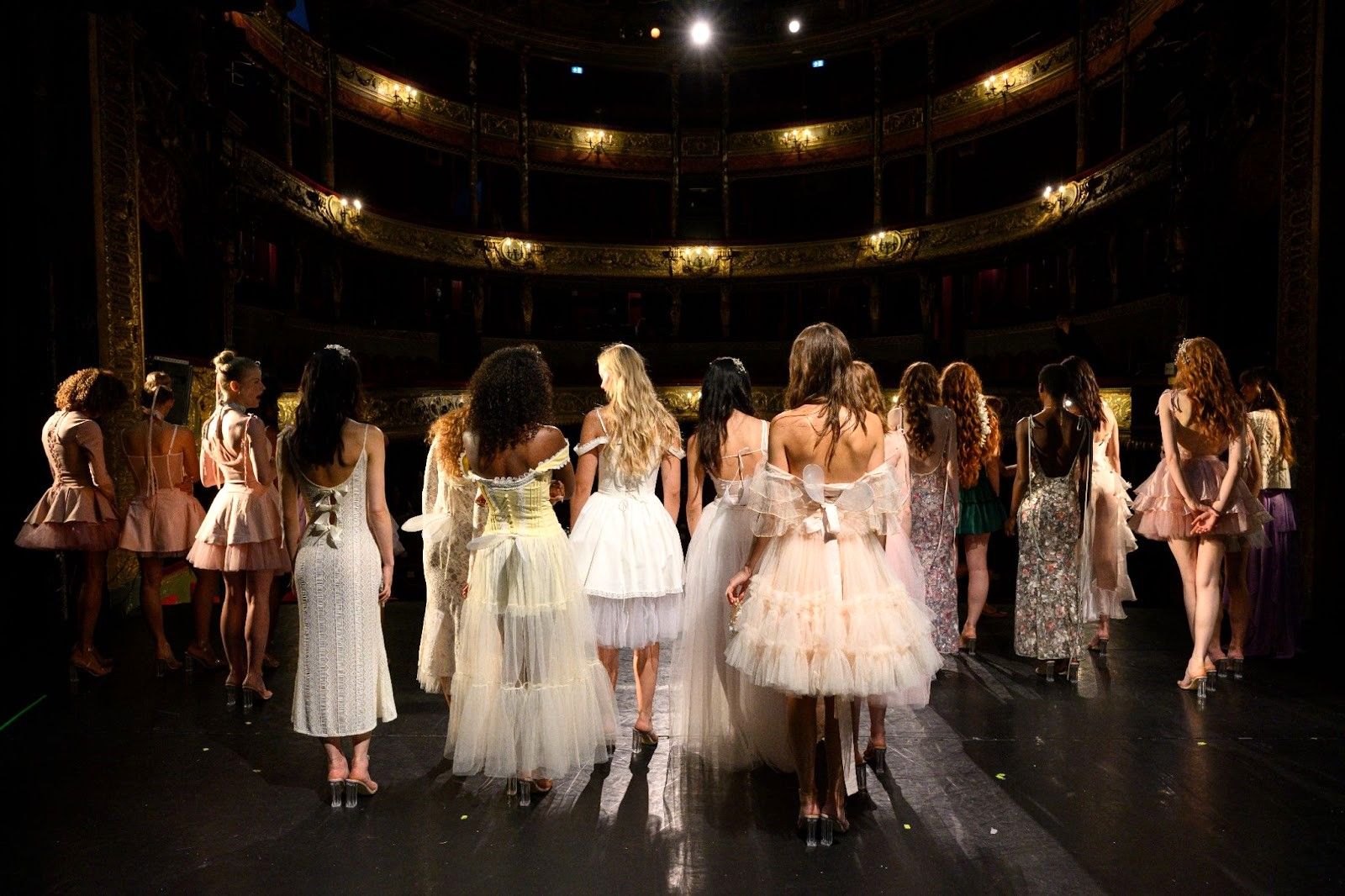Models in pastel dresses on theater stage