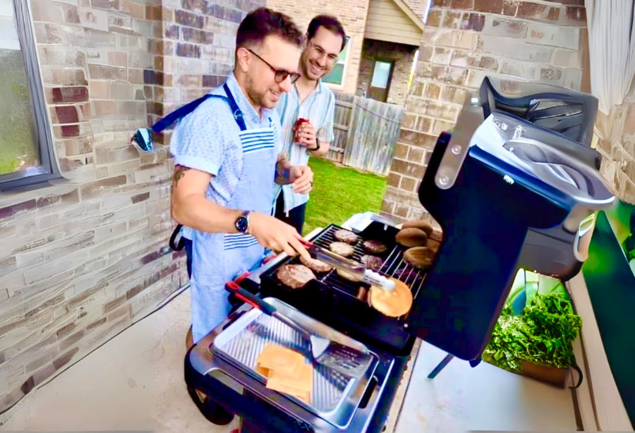 Two men grilling burgers on a patio grill
