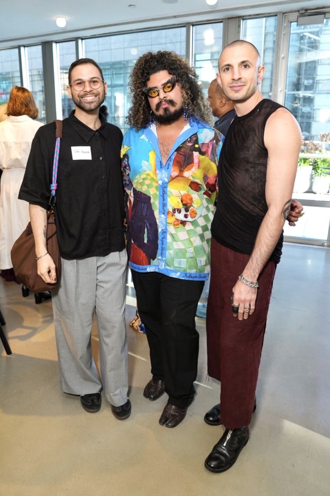 Three fashionable people posing at indoor event