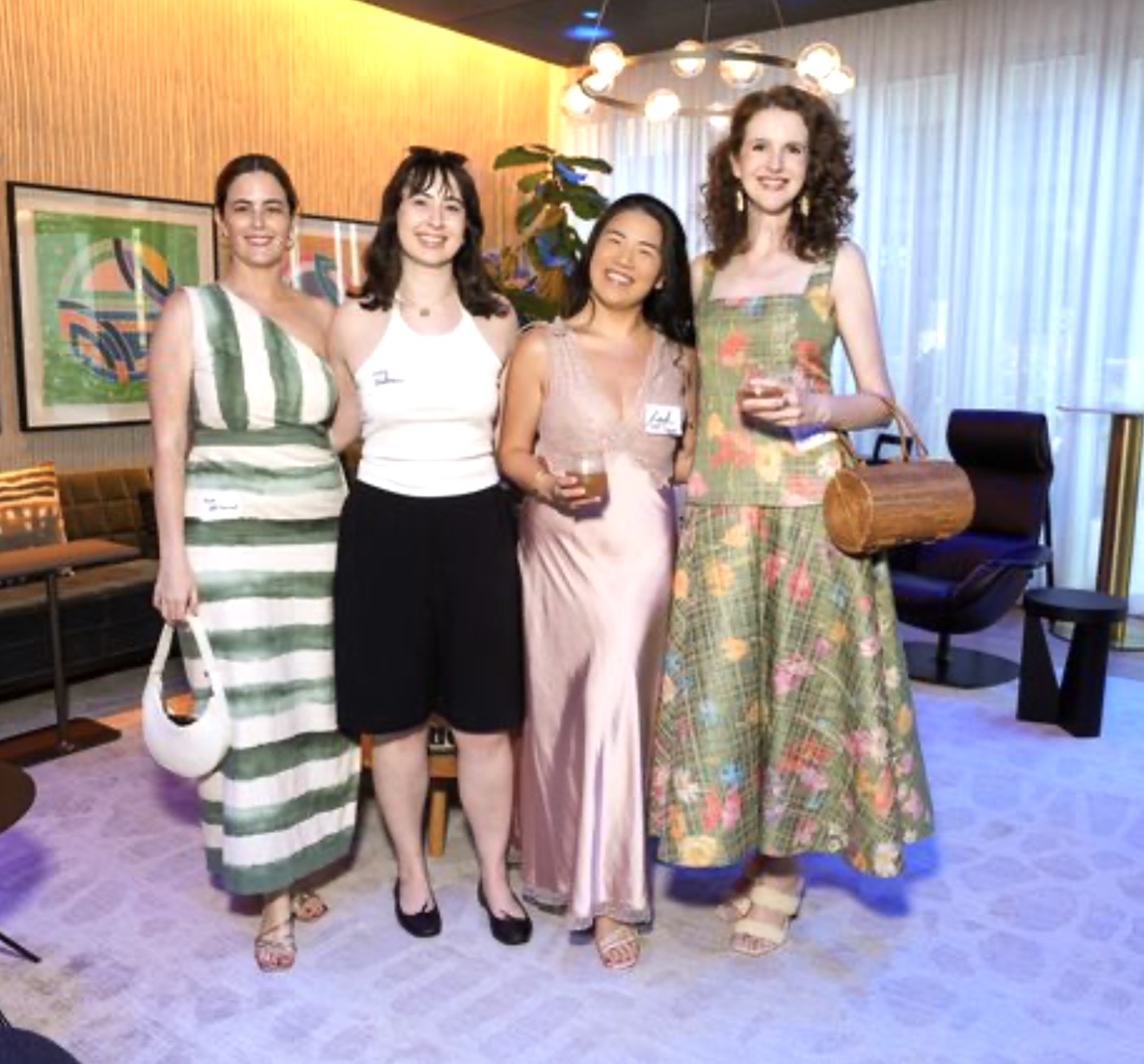 Four women smiling and holding drinks in lounge