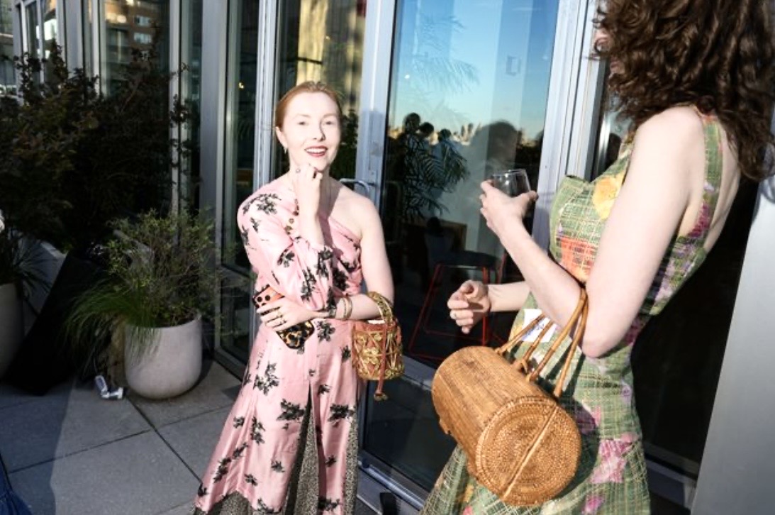 Two women in dresses chatting on rooftop balcony