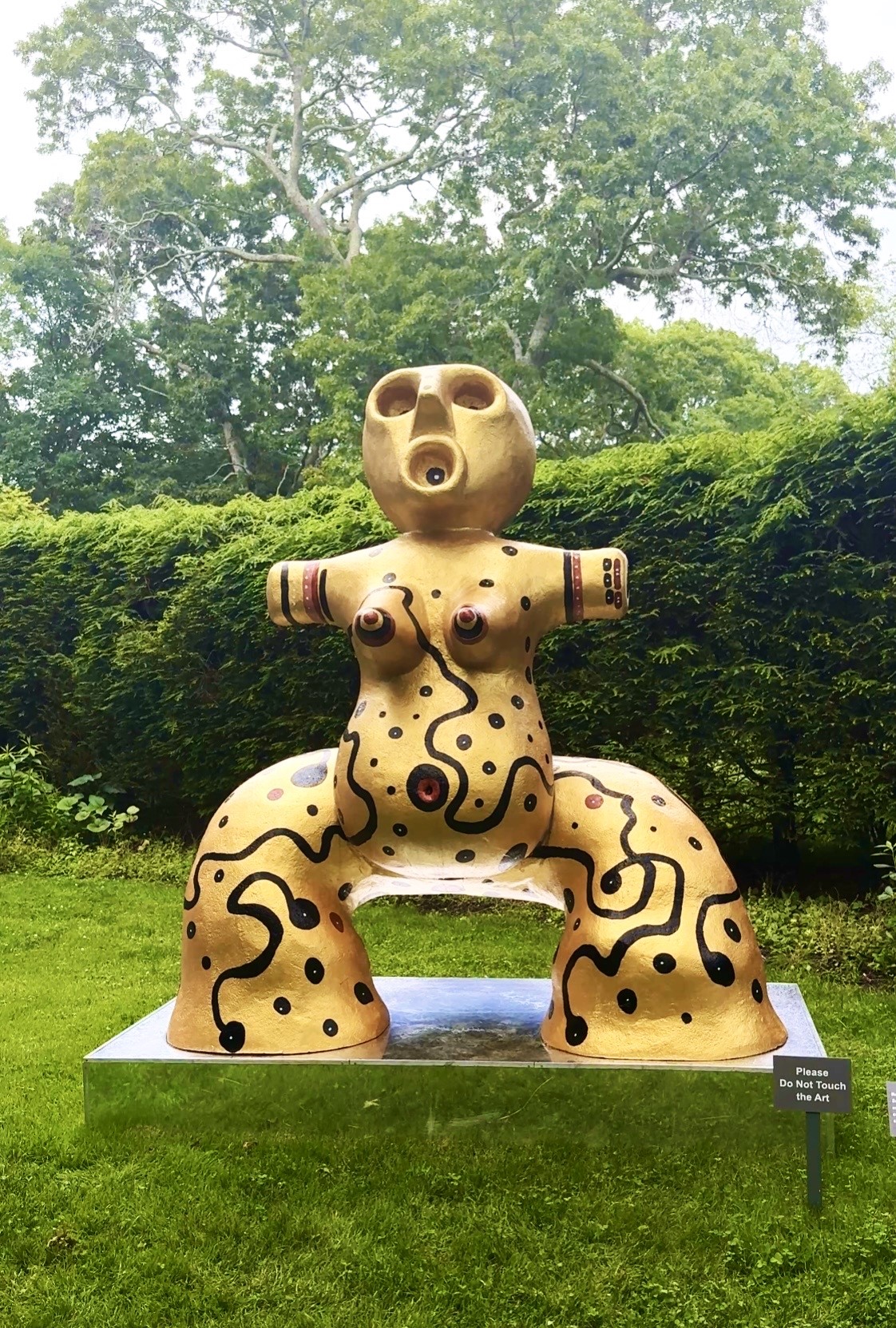Abstract painted yellow sculpture of seated figure