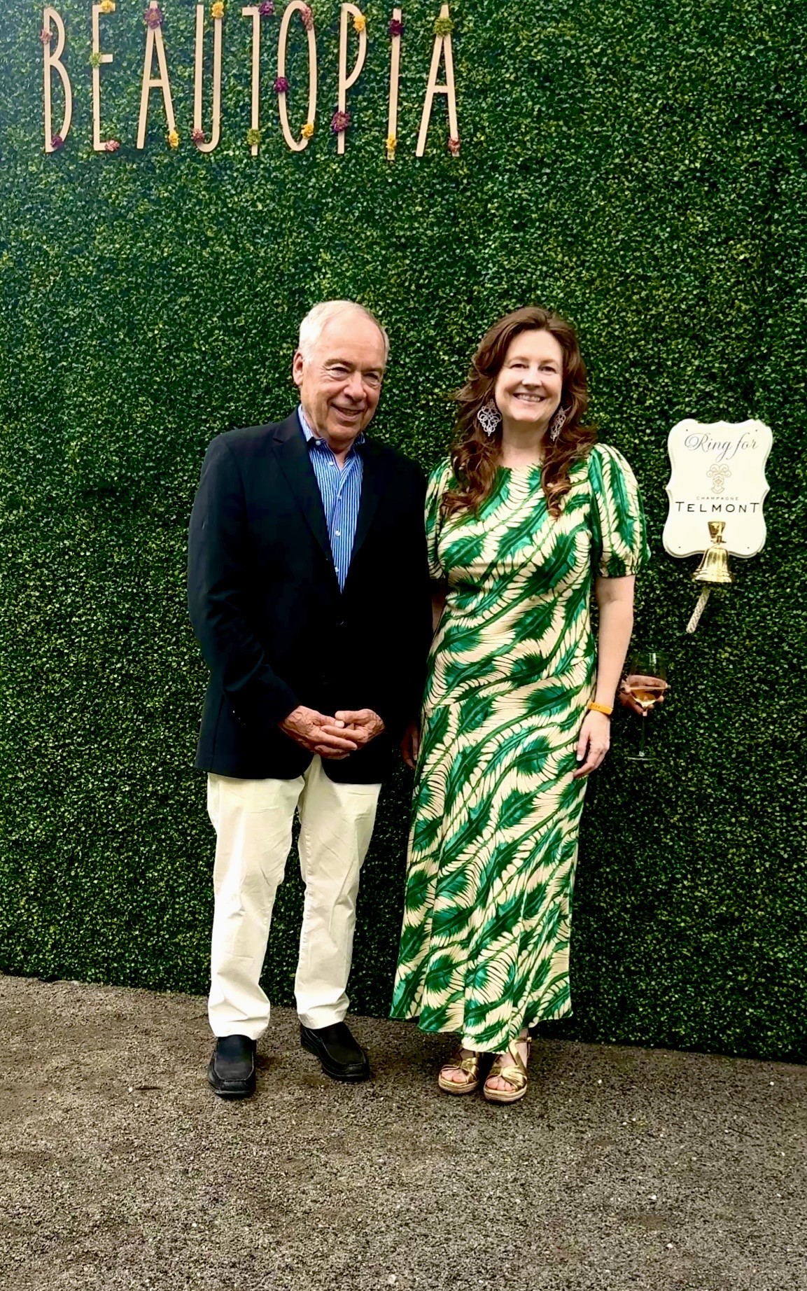 Two people posing in front of Beautopia wall
