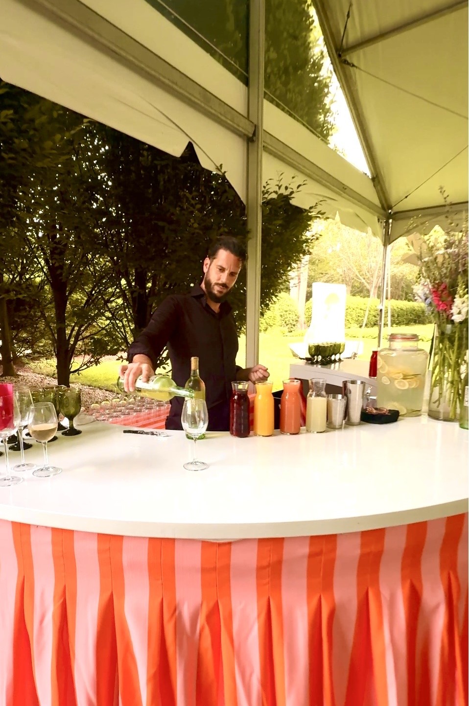 Bartender pouring drink at outdoor tent bar