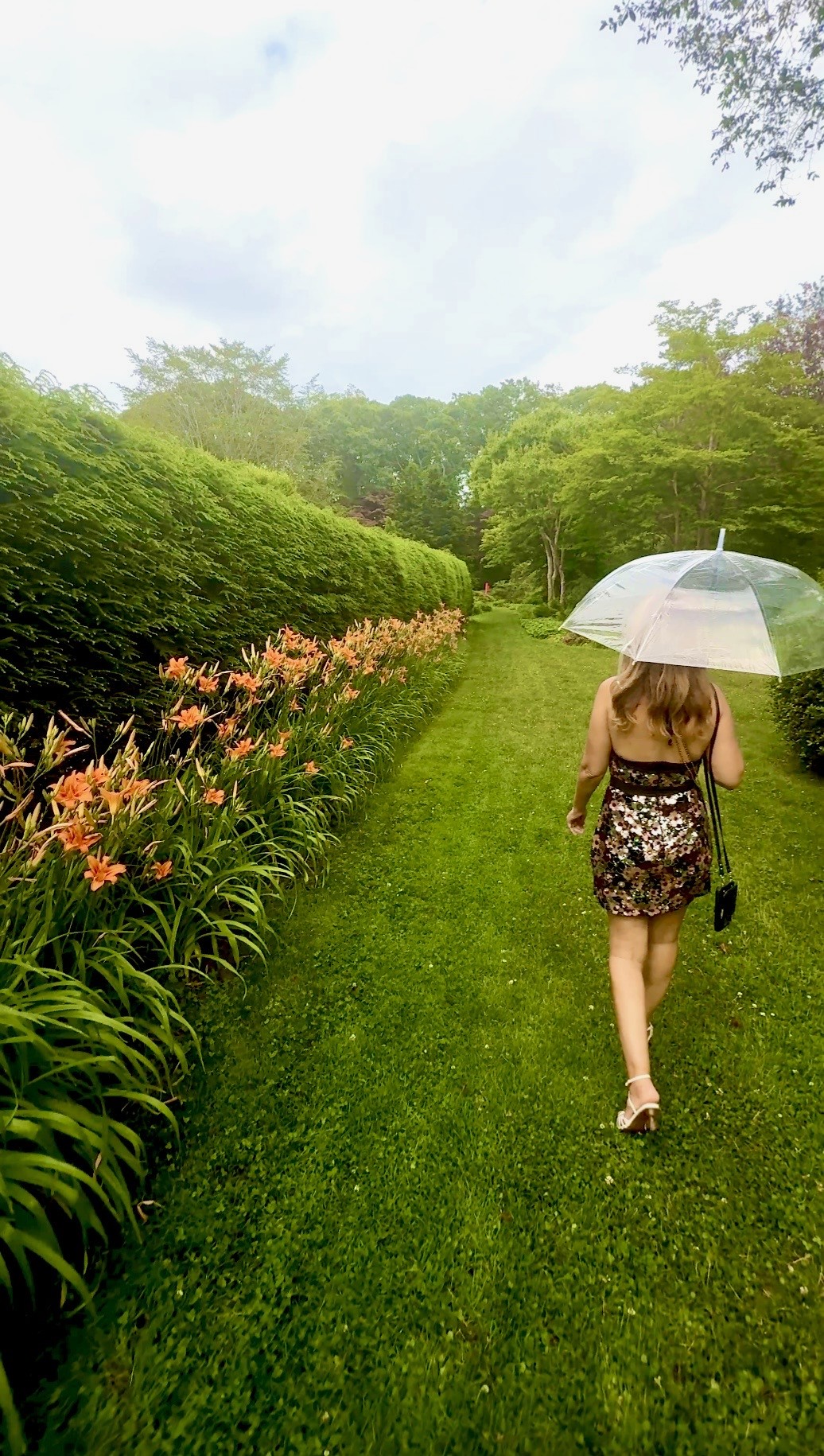Person walking down grassy path with umbrella