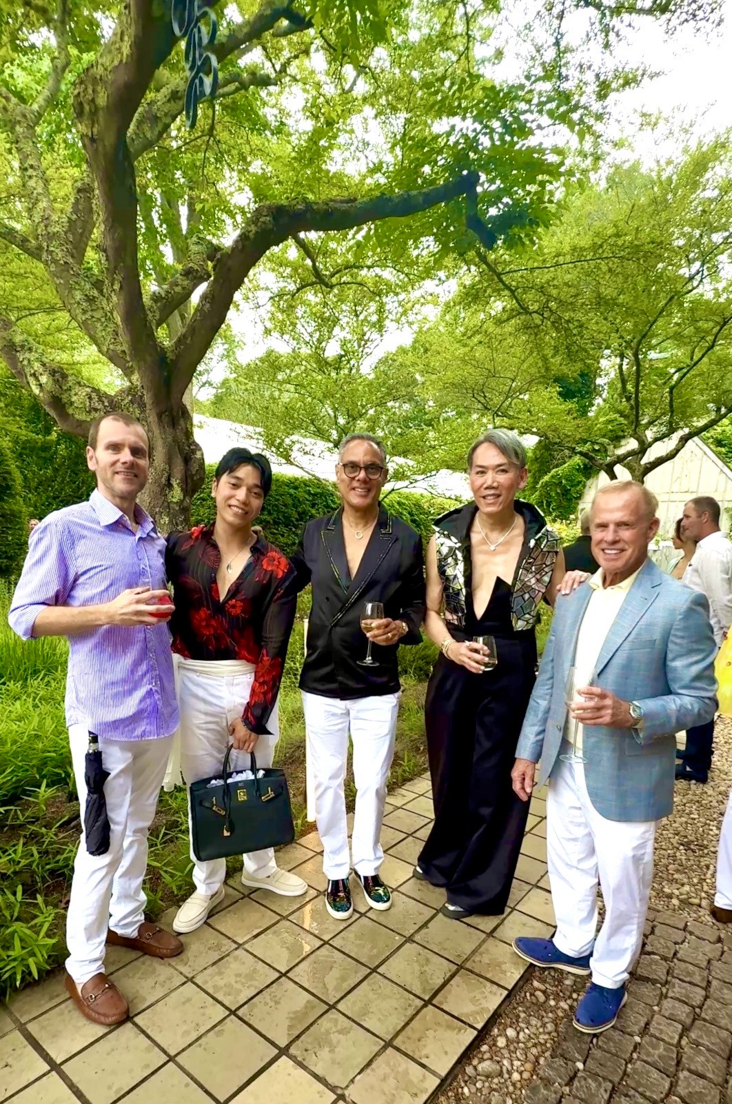 Five well-dressed people outdoors holding drinks