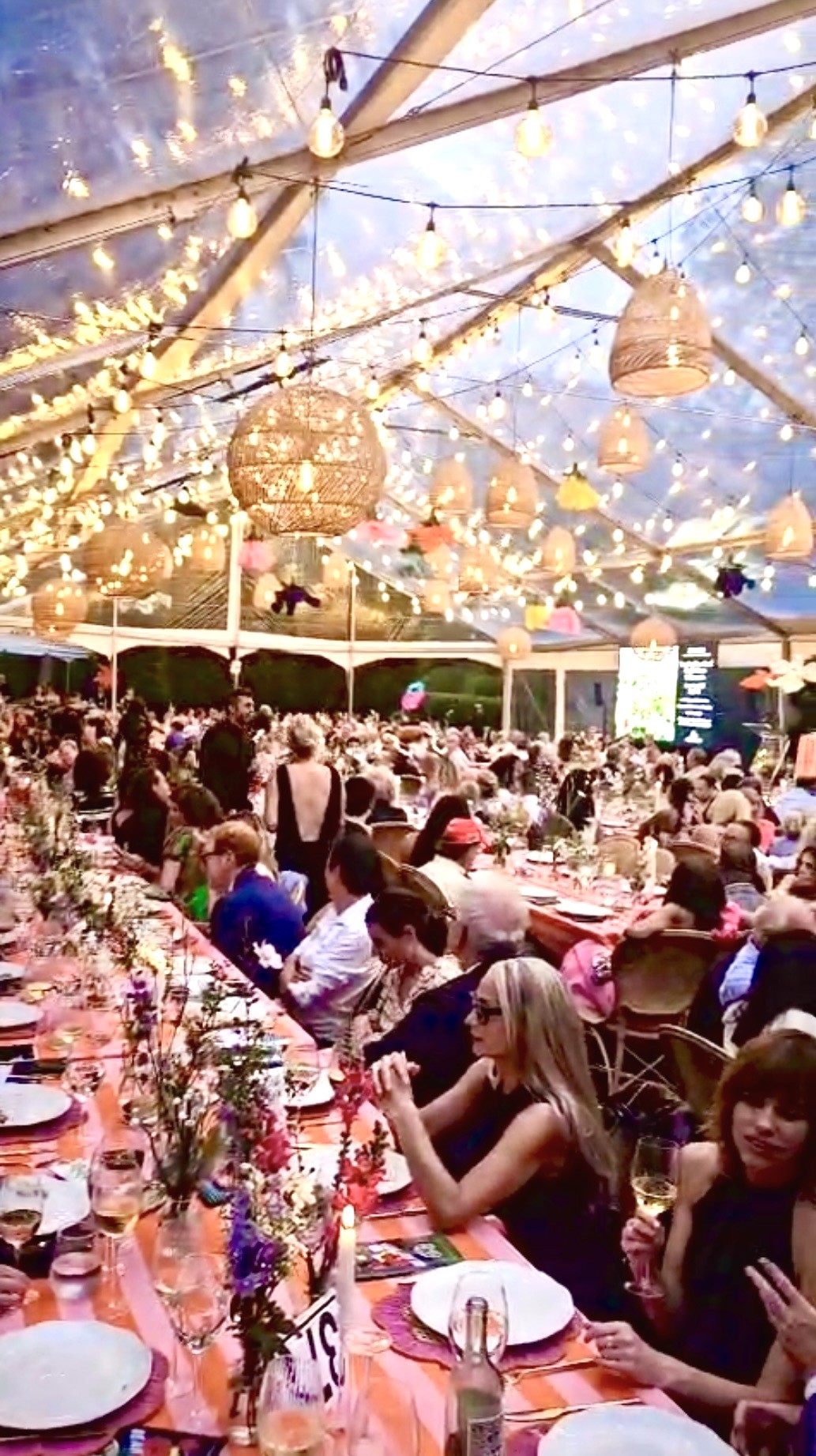 Crowded outdoor banquet under string lights