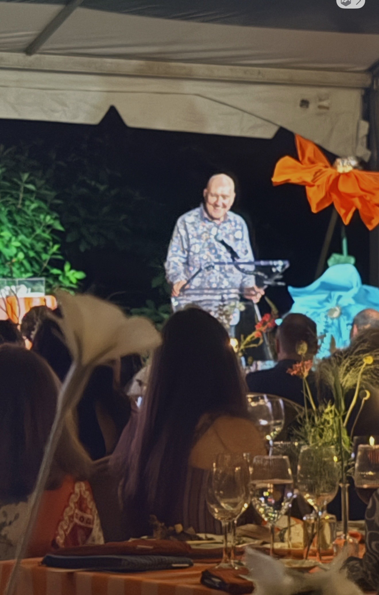 Man speaking at outdoor dinner under tent