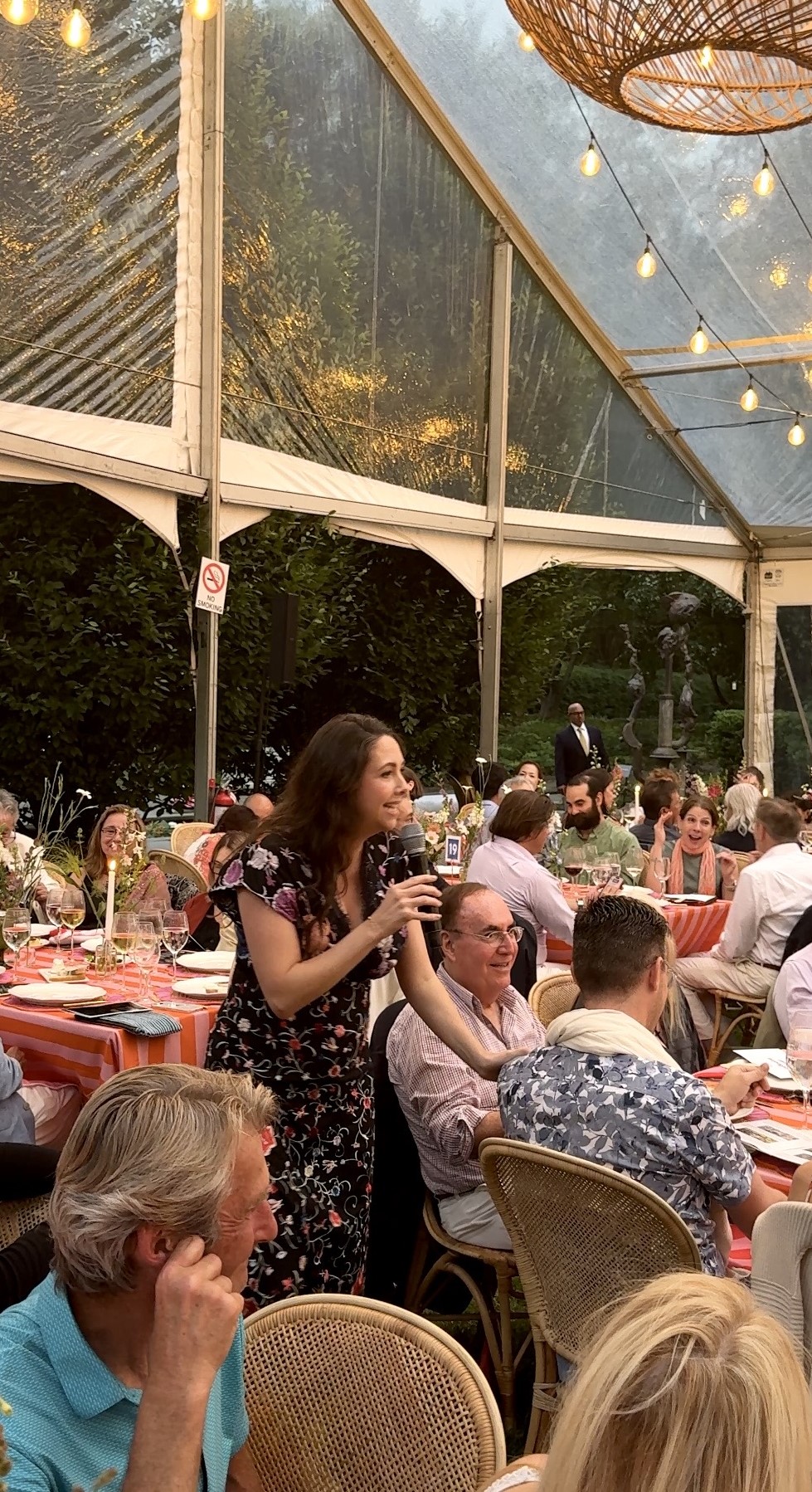Woman speaking at tented outdoor dinner party