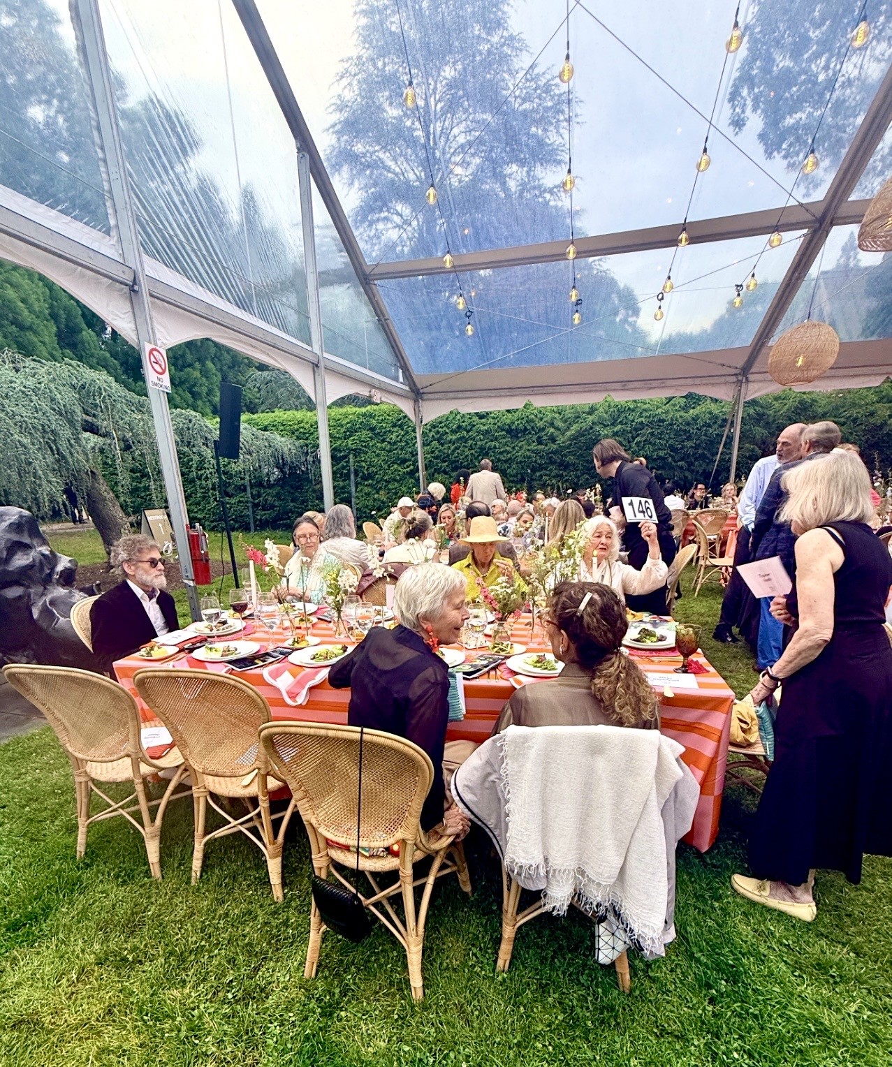 Guests at outdoor tented dinner under string lights