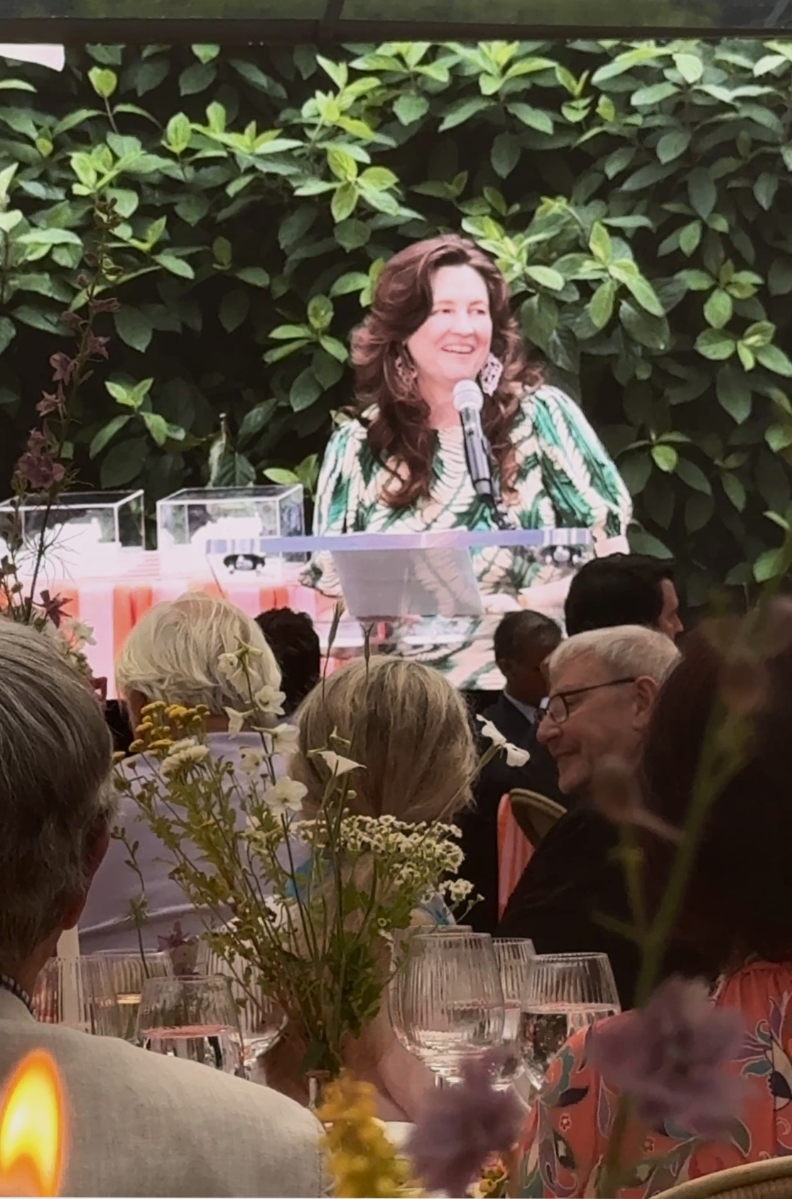 Smiling woman speaking at floral-decorated banquet