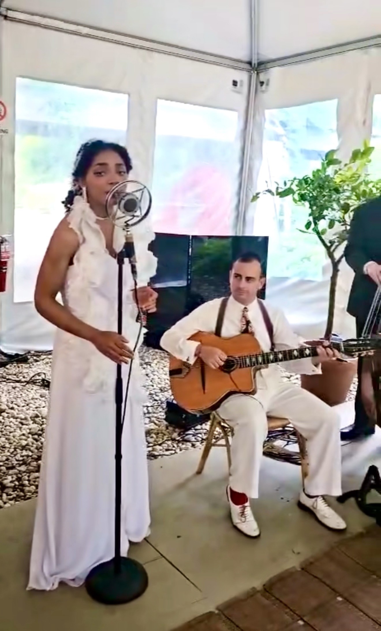 Singer and guitarist performing inside white tent